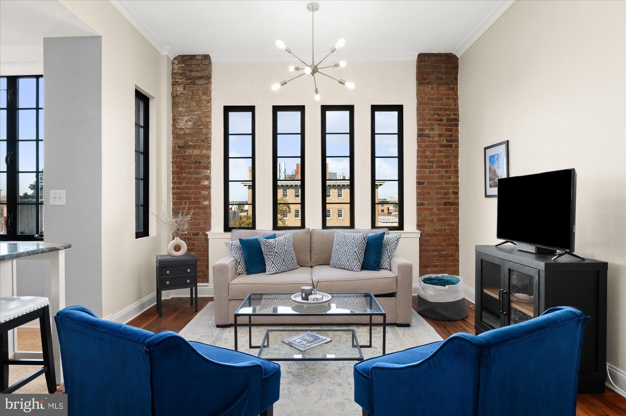a living room with furniture a flat screen tv and a large window