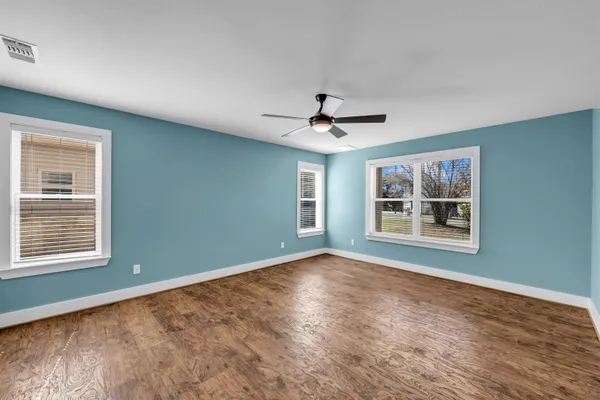 a view of an empty room with a window and wooden floor