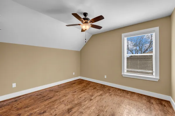 a view of empty room with wooden floor and ceiling fan