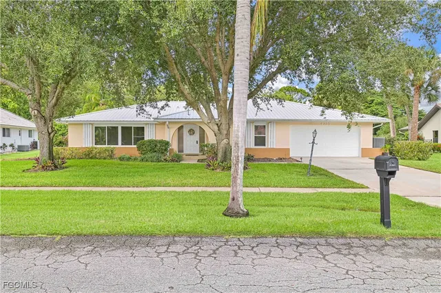 a front view of a house with a yard and trees