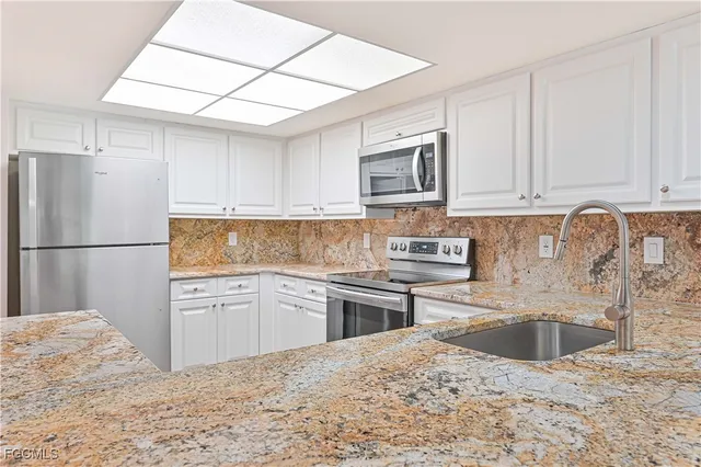 a kitchen with granite countertop a refrigerator sink stove and microwave