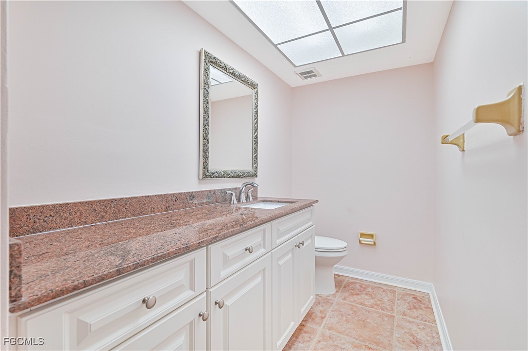 4255 Glasgow Court North Fort Myers, FL 33903 - Photo 32 of 35 a bathroom with a granite countertop sink a toilet and a mirror