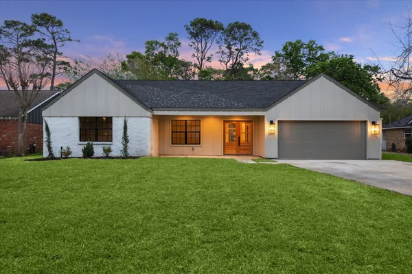a view of a house with a big yard potted plants and large tree