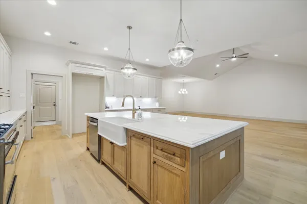 a hall with kitchen island a stove a sink a refrigerator and a table