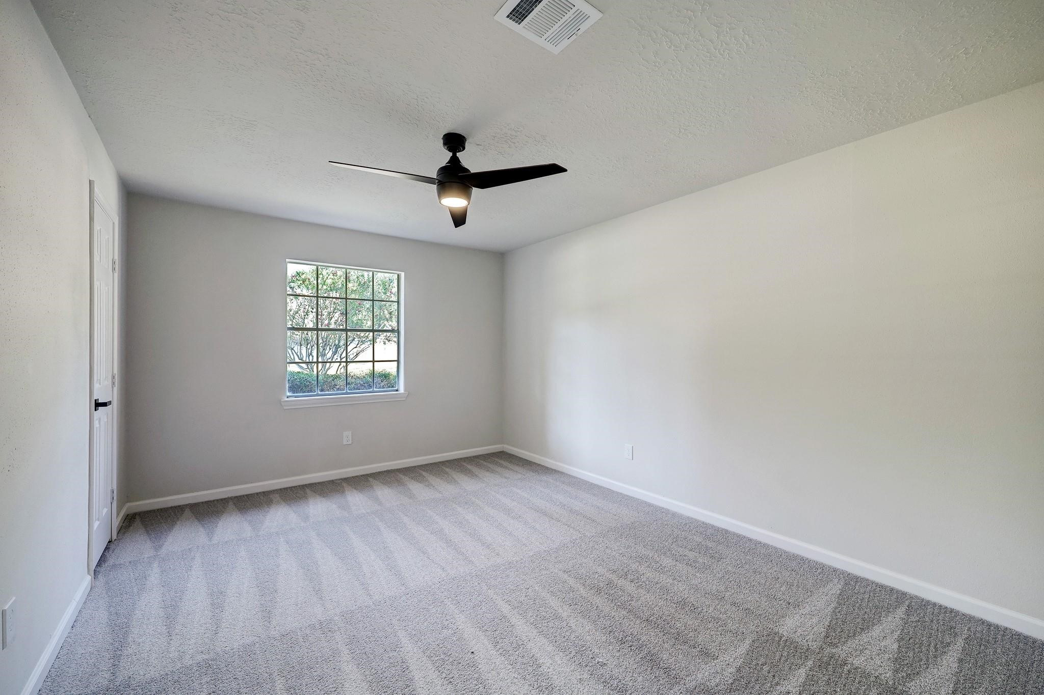 9723 Galston Lane Spring, TX 77379 - Photo 17 of 24 Equally spacious, this additional bedroom includes a large window, soft carpeting underfoot, and a ceiling fan. Ideal for guests, an office, or a creative space.
