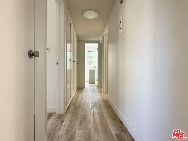 a view of a hallway with wooden floor and a bathroom