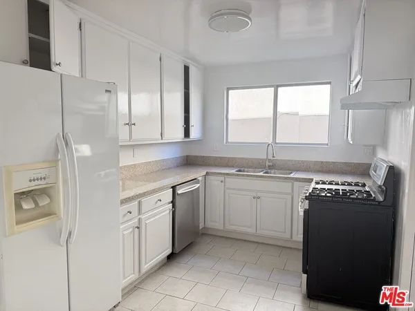 a kitchen with granite countertop a sink window and refrigerator