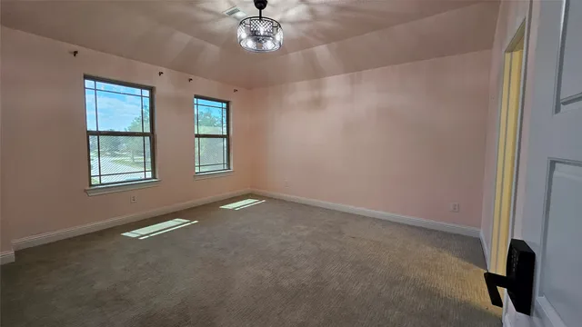 en empty room with windows and chandelier fan