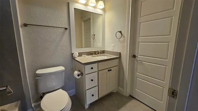 a bathroom with a granite countertop toilet sink and mirror
