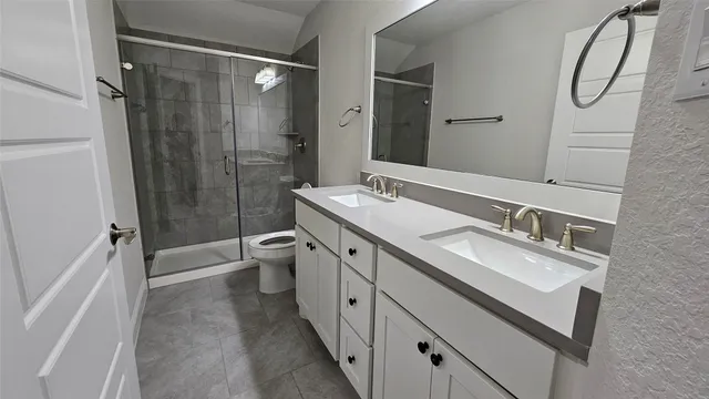 a spacious bathroom with a double vanity sink toilet mirror and shower