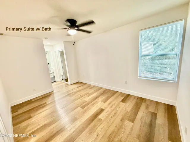 a view of a room with wooden floor and a ceiling fan