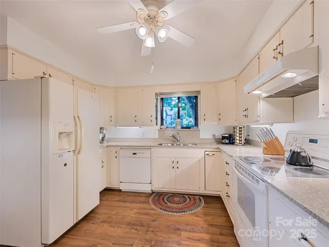 a large kitchen with a sink dishwasher a stove a refrigerator and a dining table with wooden floor