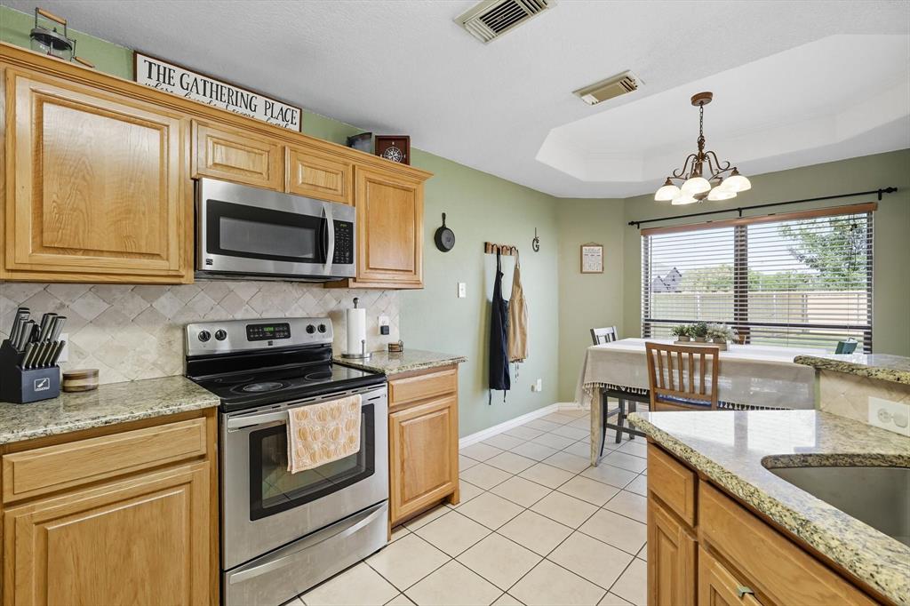 100 Turtle Dove Krum, TX 76249 - Photo 21 of 40 a kitchen with granite countertop a stove a sink and a microwave
