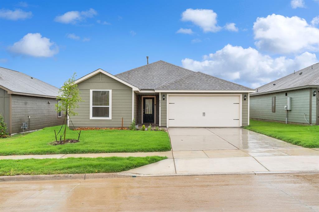 Ranch-style home with an attached garage, a shingled roof, a front yard, and concrete driveway