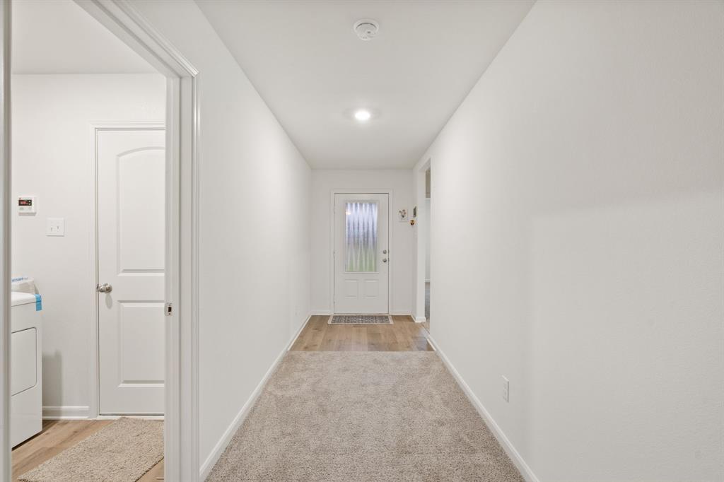 8216 Columbia Falls Road Ponder, TX 76259 - Photo 17 of 28 Corridor featuring light colored carpet, baseboards, and washer / dryer