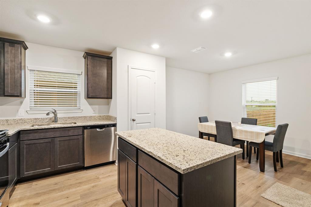 8216 Columbia Falls Road Ponder, TX 76259 - Photo 7 of 28 Kitchen featuring dark brown cabinets, a sink, light wood-style flooring, stainless steel dishwasher, and a kitchen island