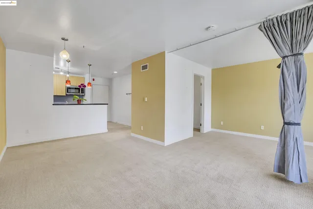 an empty room with kitchen and windows