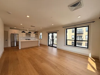 a view of an empty room with a window and wooden floor