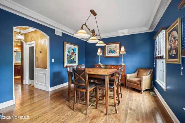 a kitchen with stainless steel appliances granite countertop a stove a refrigerator a oven a sink a dining table and chairs with wooden floor