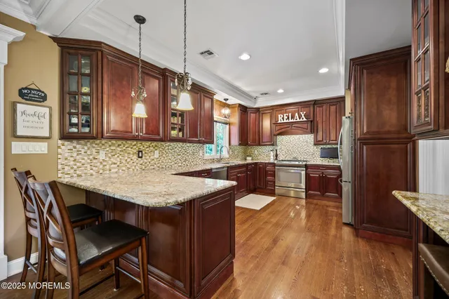 a kitchen with stainless steel appliances granite countertop wooden cabinets a sink and dishwasher a stove top oven with wooden floor