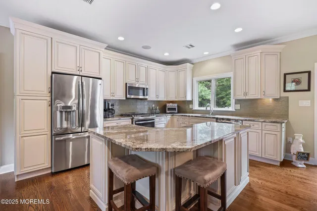 a kitchen with kitchen island granite countertop white cabinets and stainless steel appliances