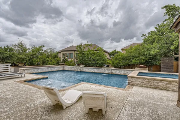 a view of swimming pool with outdoor seating and trees in the background