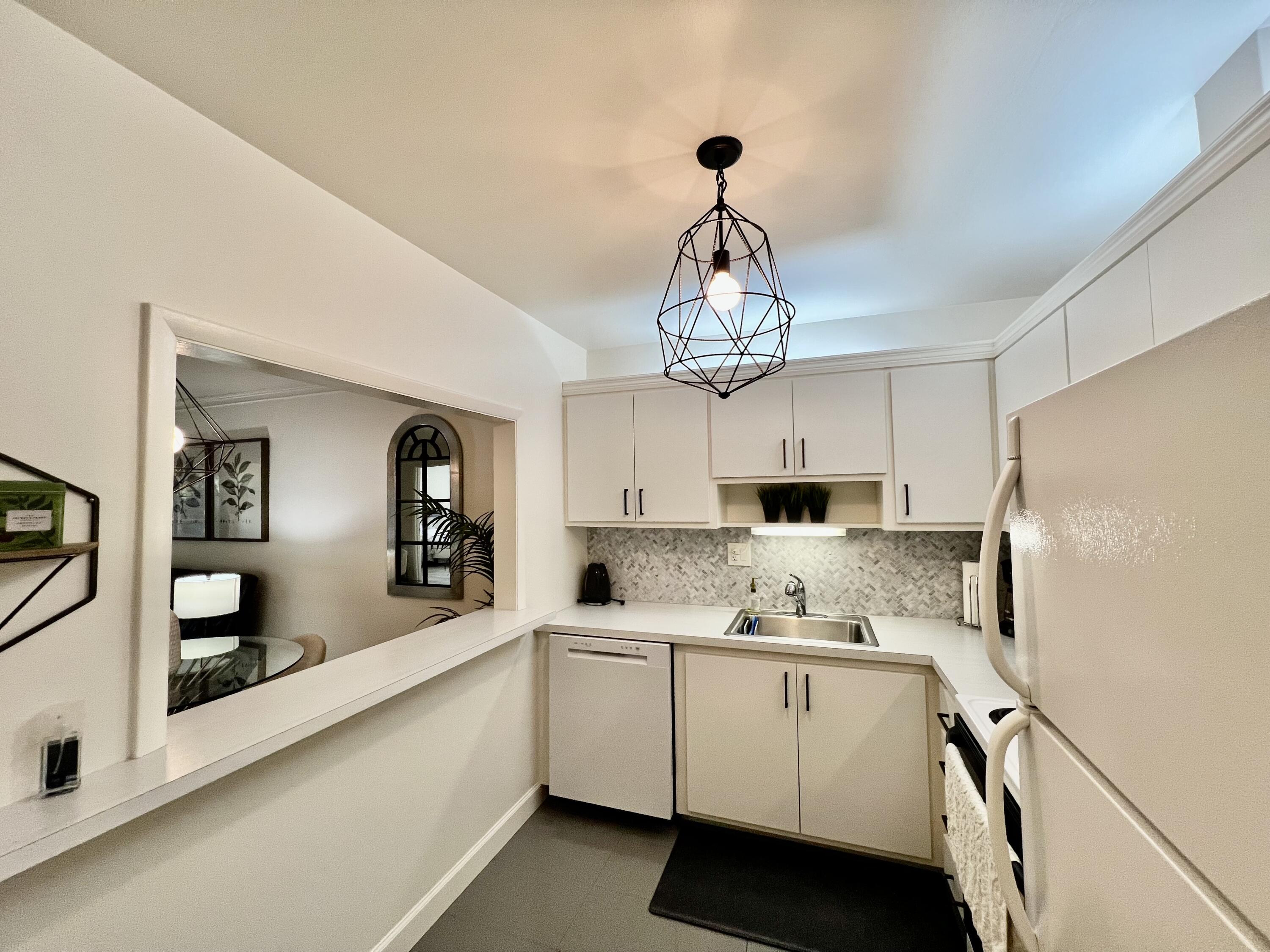 5640 Southwest 3rd Place, Unit 217 Margate, FL 33068 - Photo 20 of 32 a kitchen with kitchen island white cabinets and white appliances