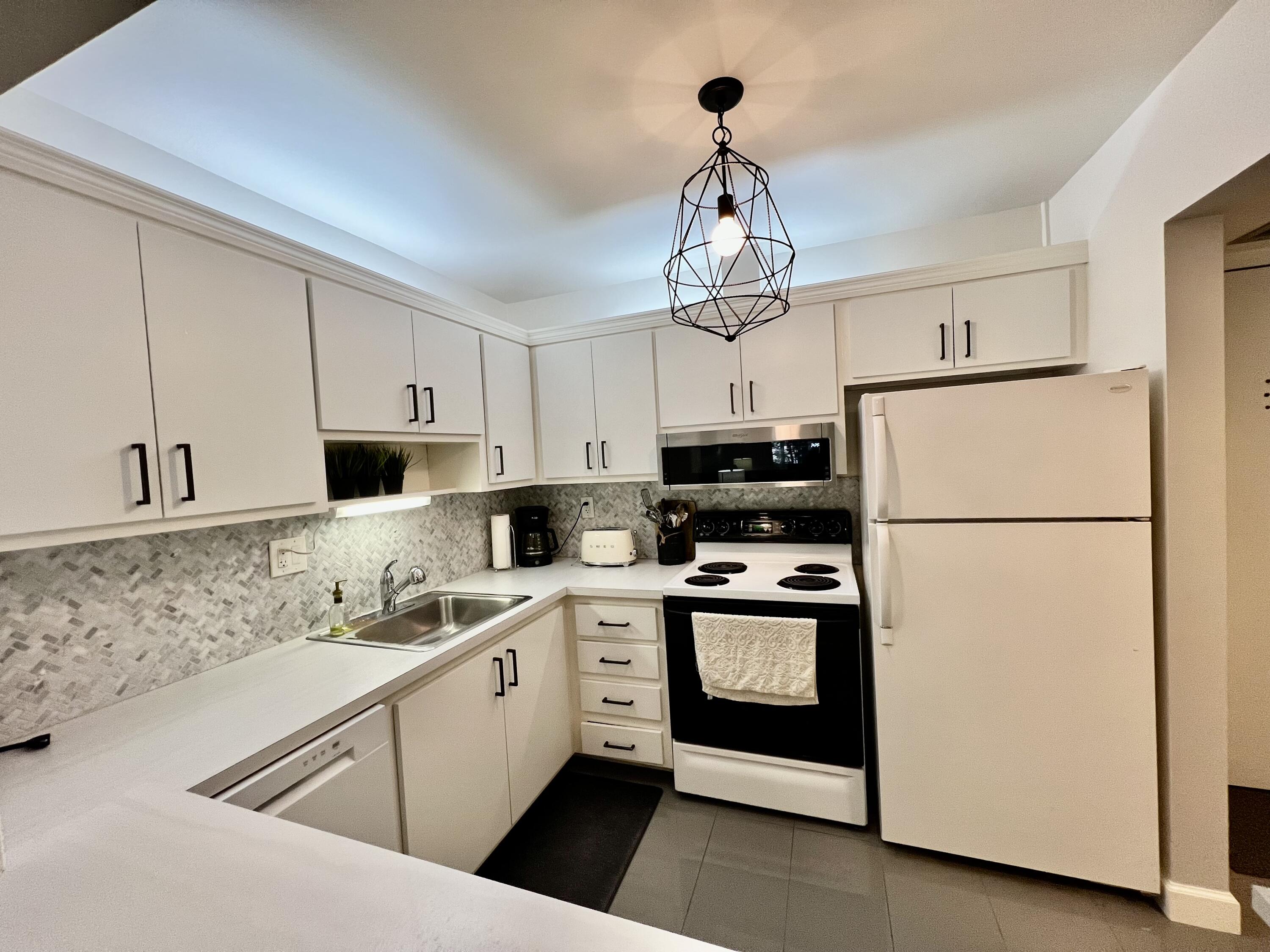 5640 Southwest 3rd Place, Unit 217 Margate, FL 33068 - Photo 4 of 32 a kitchen with stainless steel appliances granite countertop a sink a refrigerator a stove a microwave and cabinets