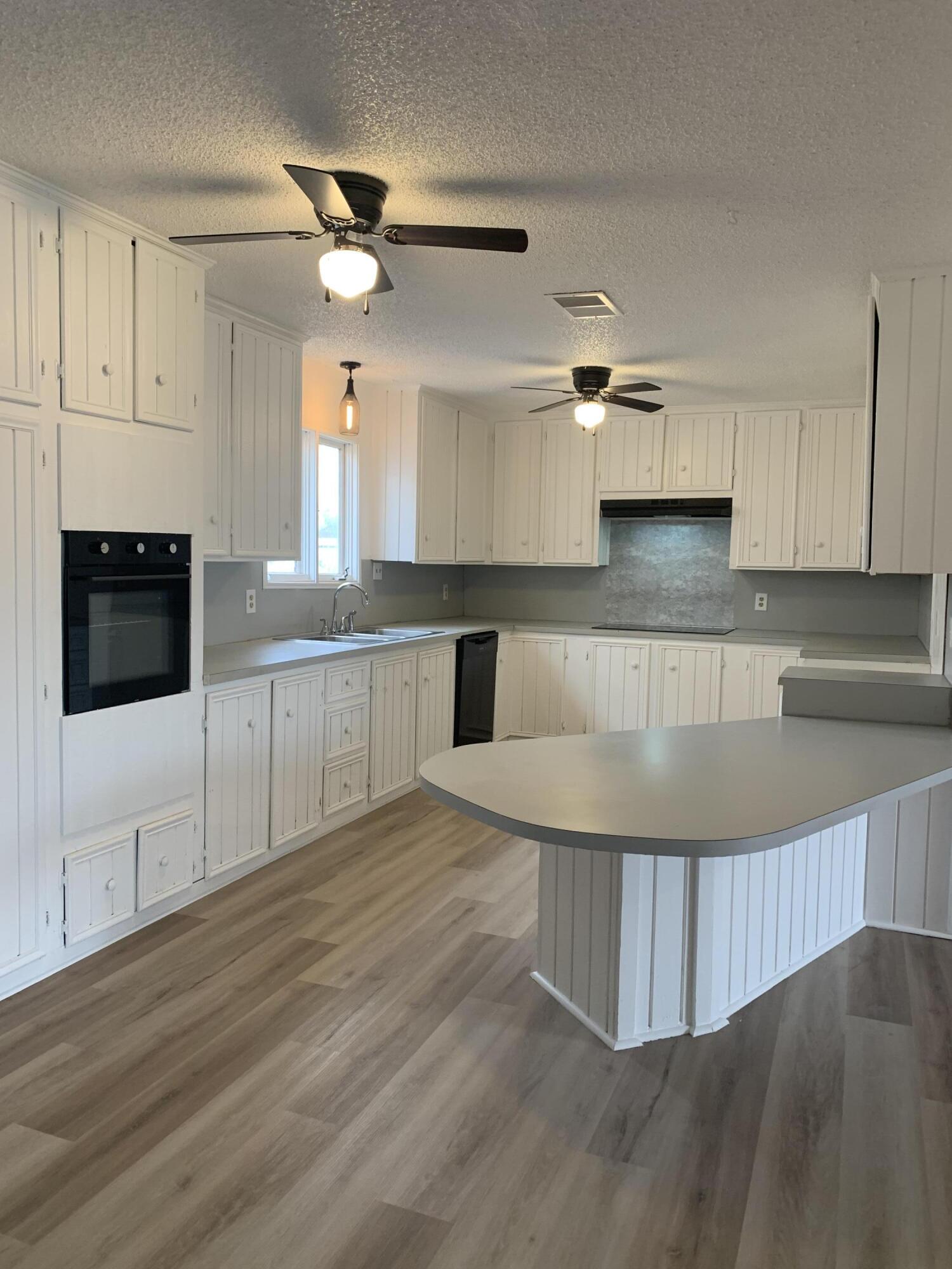 750 South 13th Street Slaton, TX 79364 - Photo 4 of 13 a kitchen with stainless steel appliances kitchen island granite countertop a stove a sink and white cabinets