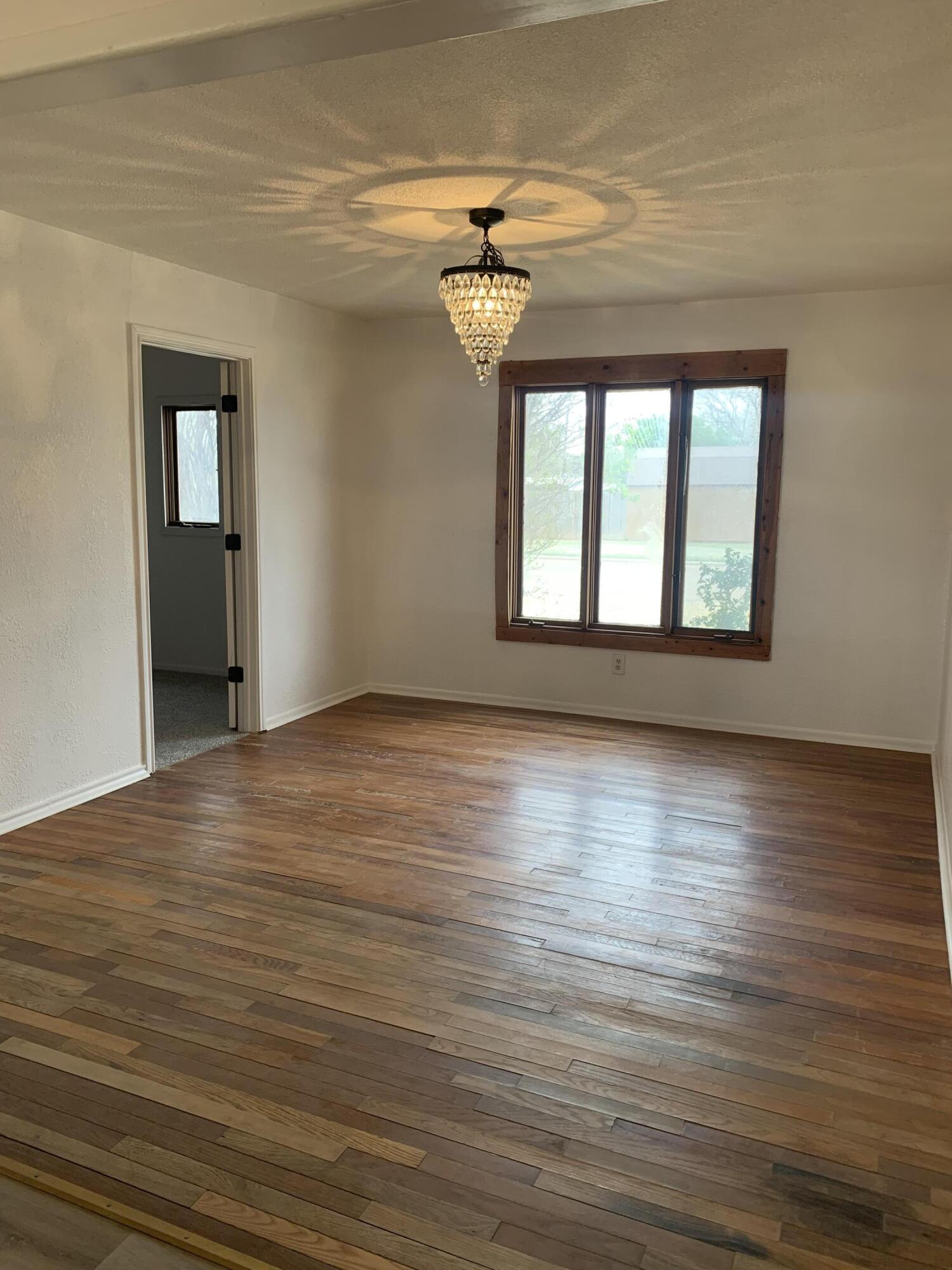 750 South 13th Street Slaton, TX 79364 - Photo 5 of 13 a view of empty room with wooden floor and fan