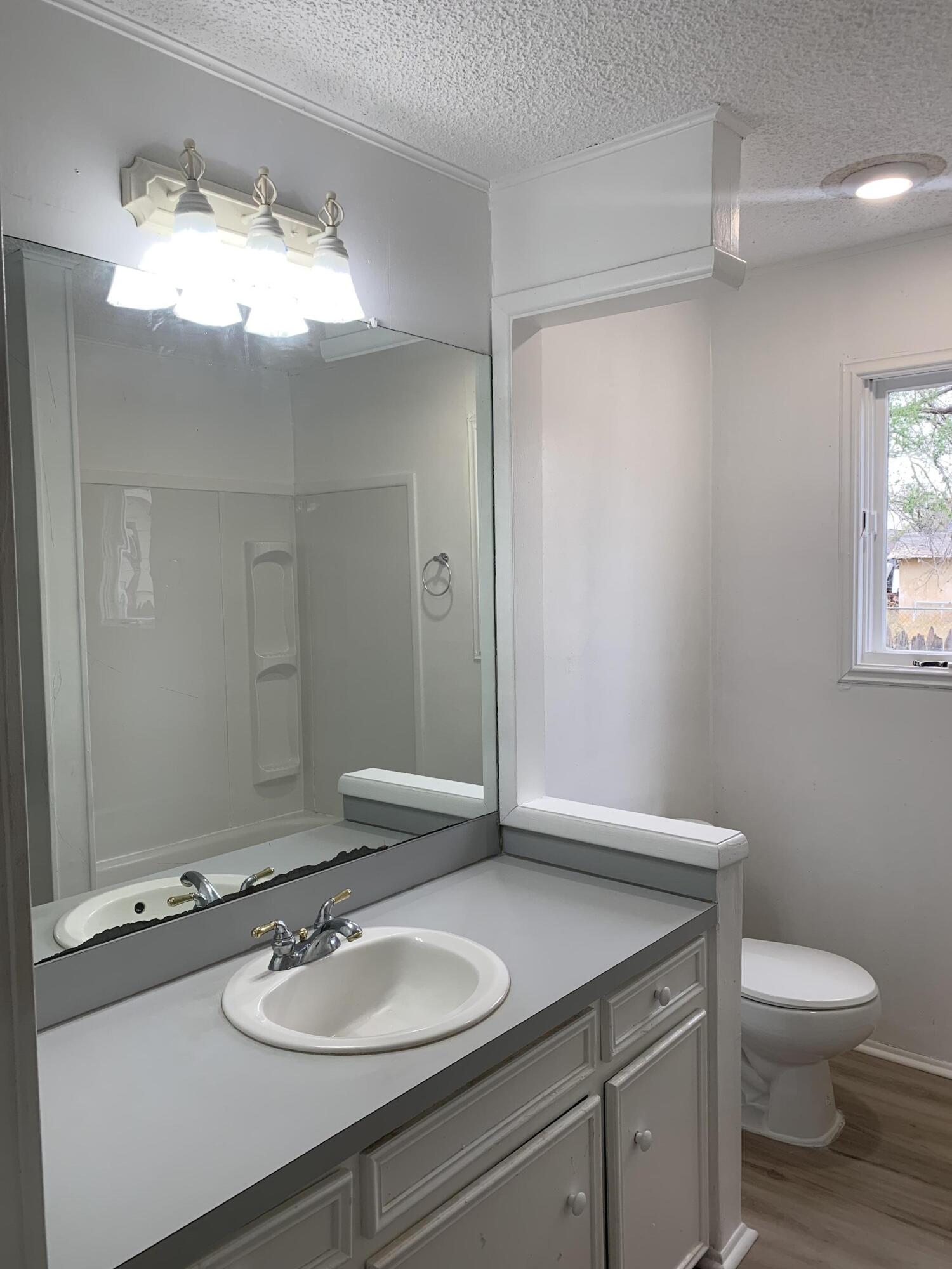 750 South 13th Street Slaton, TX 79364 - Photo 8 of 13 a bathroom with a granite countertop sink toilet and mirror