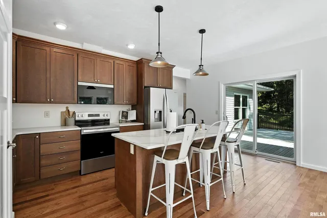 a kitchen with stainless steel appliances granite countertop a stove top oven a refrigerator a sink and dishwasher with wooden floor