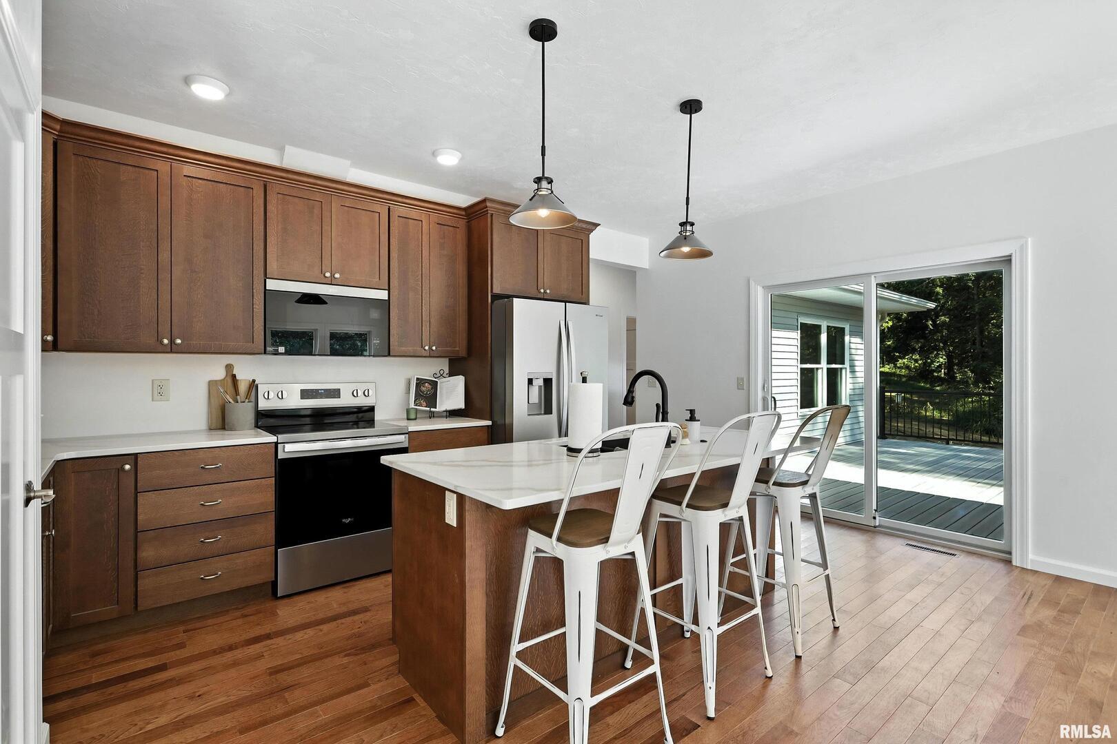 3303 Valley Drive Geneseo, IL 61254 - Photo 13 of 50 a kitchen with stainless steel appliances granite countertop a stove top oven a refrigerator a sink and dishwasher with wooden floor