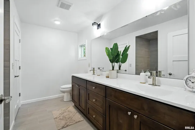a bathroom with a double vanity sink toilet and a mirror