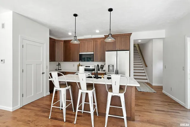 a kitchen with stainless steel appliances kitchen island granite countertop a dining table chairs and white cabinets