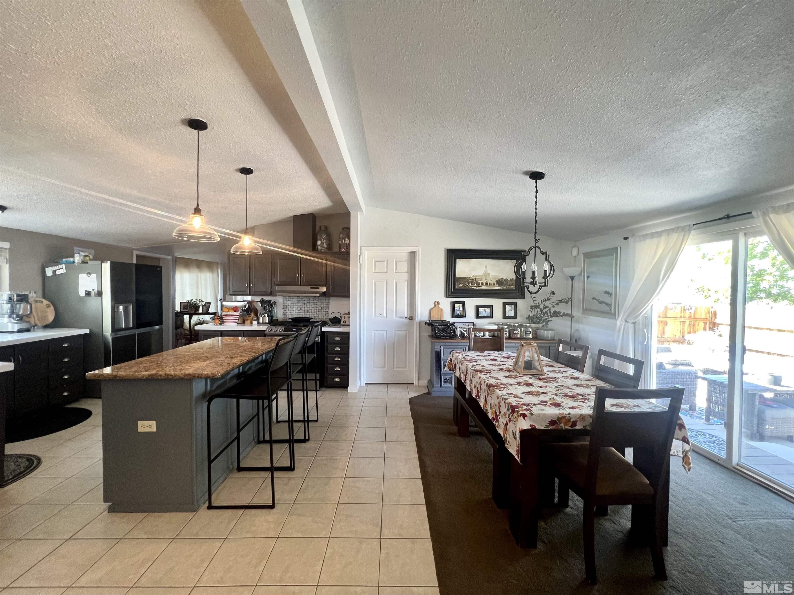 1405 South Meridian Road Lovelock, NV 89419 - Photo 29 of 39 a dining hall with stainless steel appliances kitchen island granite countertop a table chairs and a living room