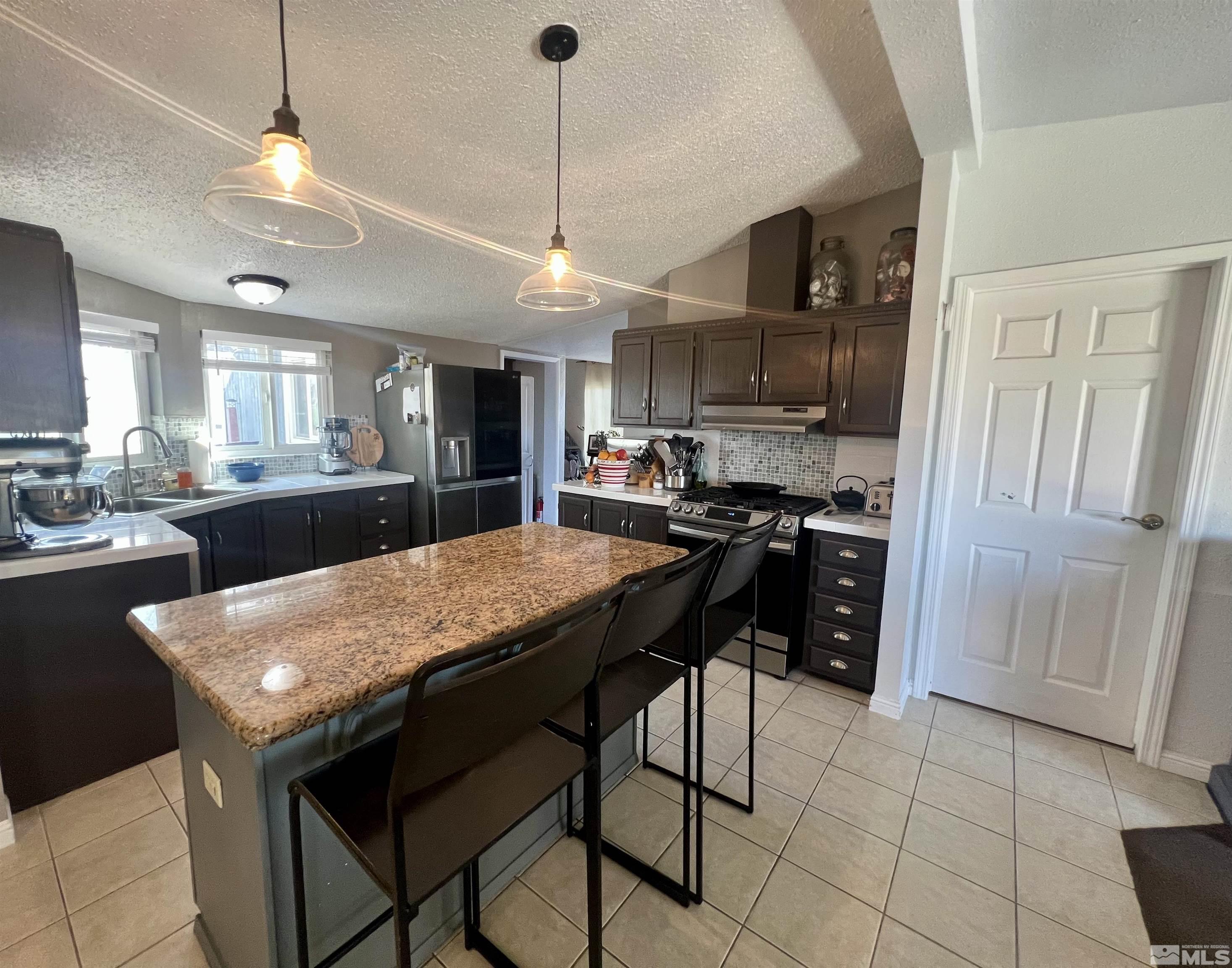 1405 South Meridian Road Lovelock, NV 89419 - Photo 33 of 39 a kitchen with a stove a refrigerator a sink a dining table and chairs