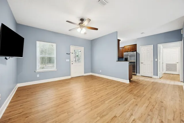 a view of empty room with wooden floor and fan