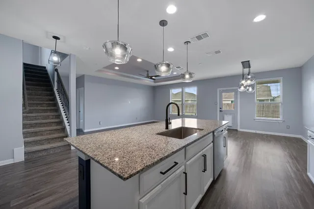 a kitchen with stainless steel appliances granite countertop a sink dishwasher and a wooden floor