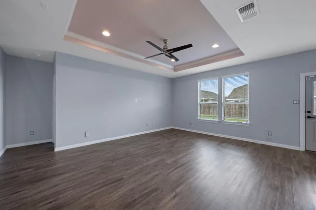 an empty room with wooden floor and windows