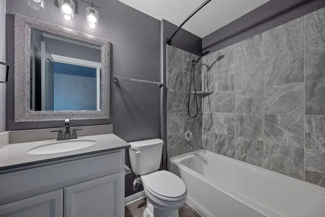 a bathroom with a toilet sink vanity tub and shower