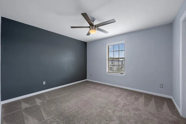 an empty room with ceiling fan and window