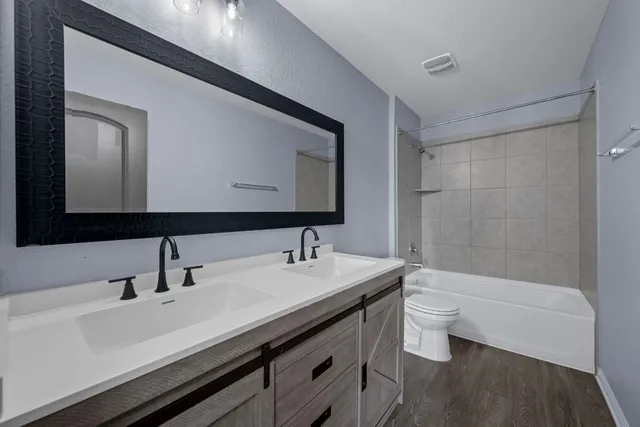 a bathroom with a double vanity sink toilet and mirror