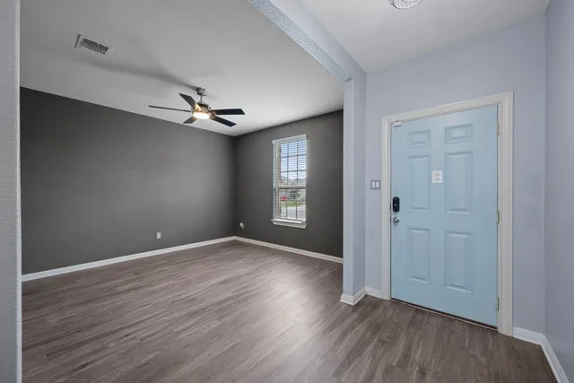 a view of an empty room with window and wooden floor