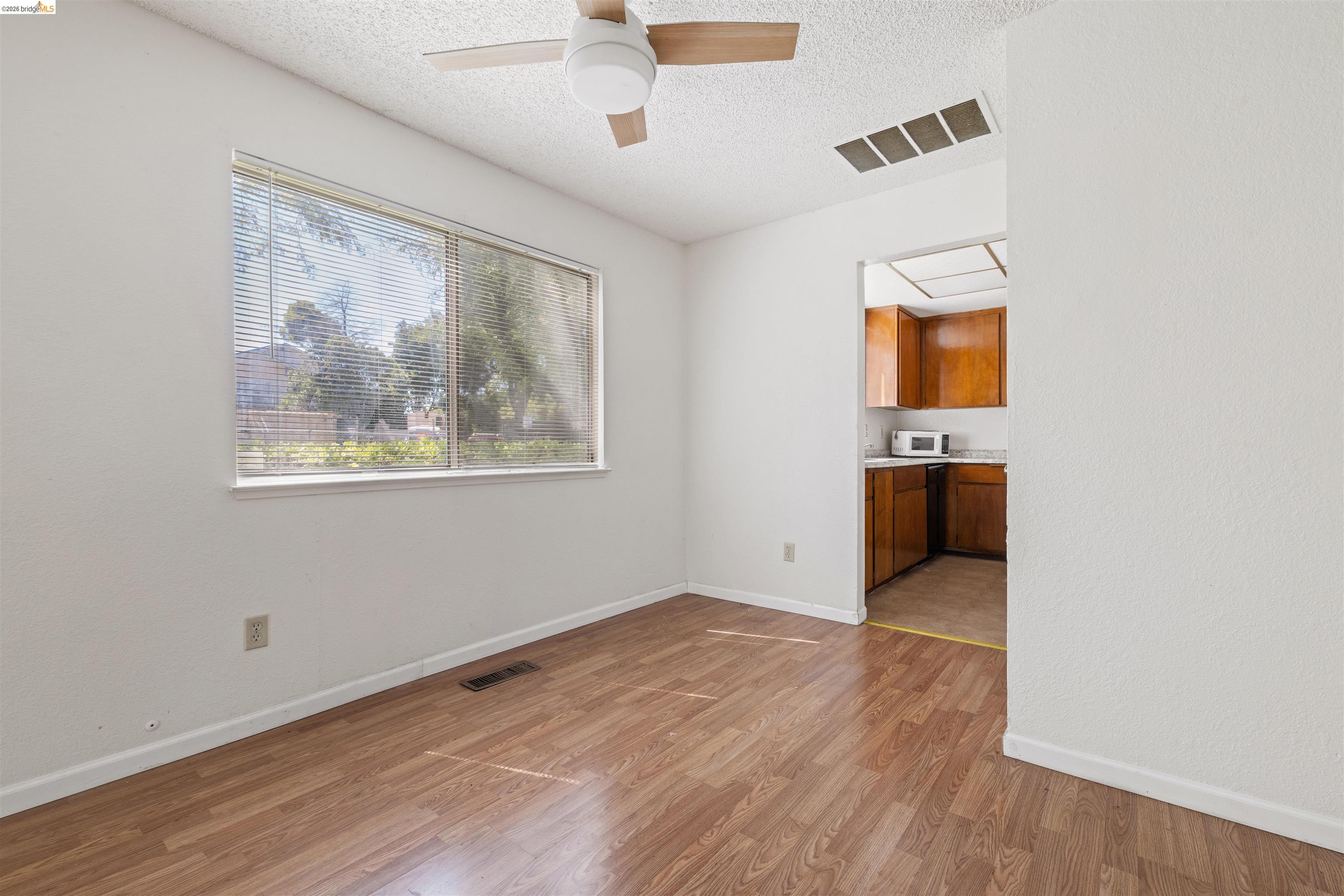 1151 Chadwick Circle Bay Point, CA 94565 - Photo 8 of 23 Room featuring wood-finish flooring, a large window with horizontal blinds, and a ceiling fan with integrated lighting