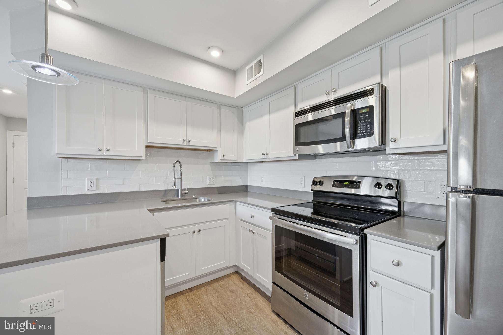 a kitchen with cabinets stainless steel appliances and wooden floor
