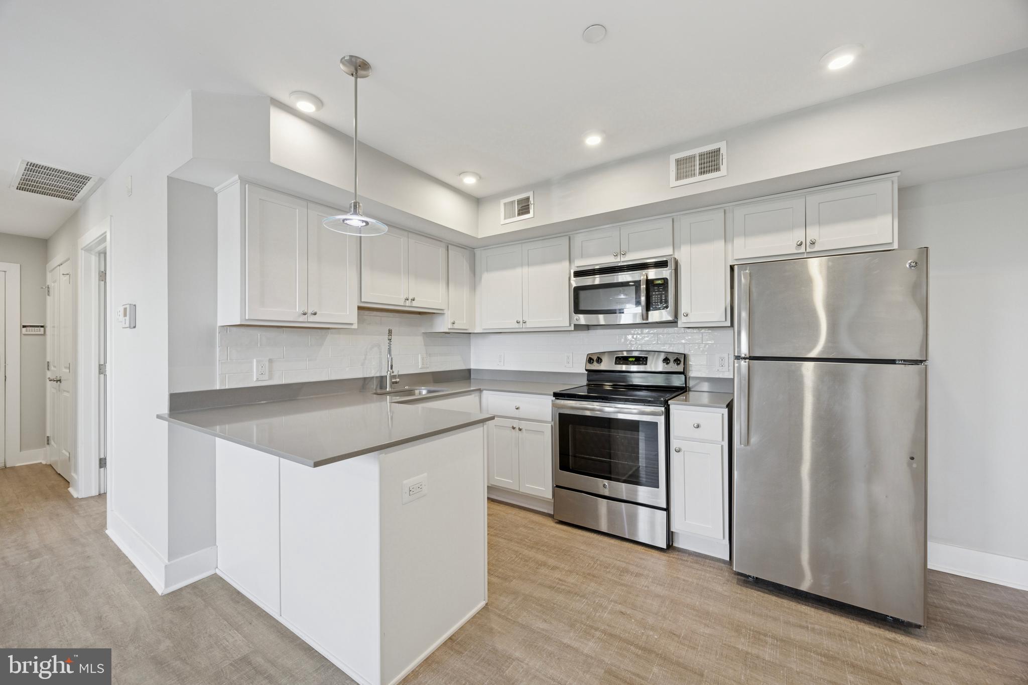 502 Gerhard Street, Unit J Philadelphia, PA 19128 - Photo 9 of 25 a kitchen with stainless steel appliances granite countertop a refrigerator stove a sink and a microwave
