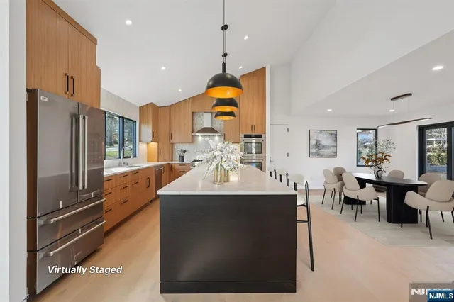 a kitchen with stainless steel appliances granite countertop a sink dishwasher a refrigerator and a dining table with wooden floor