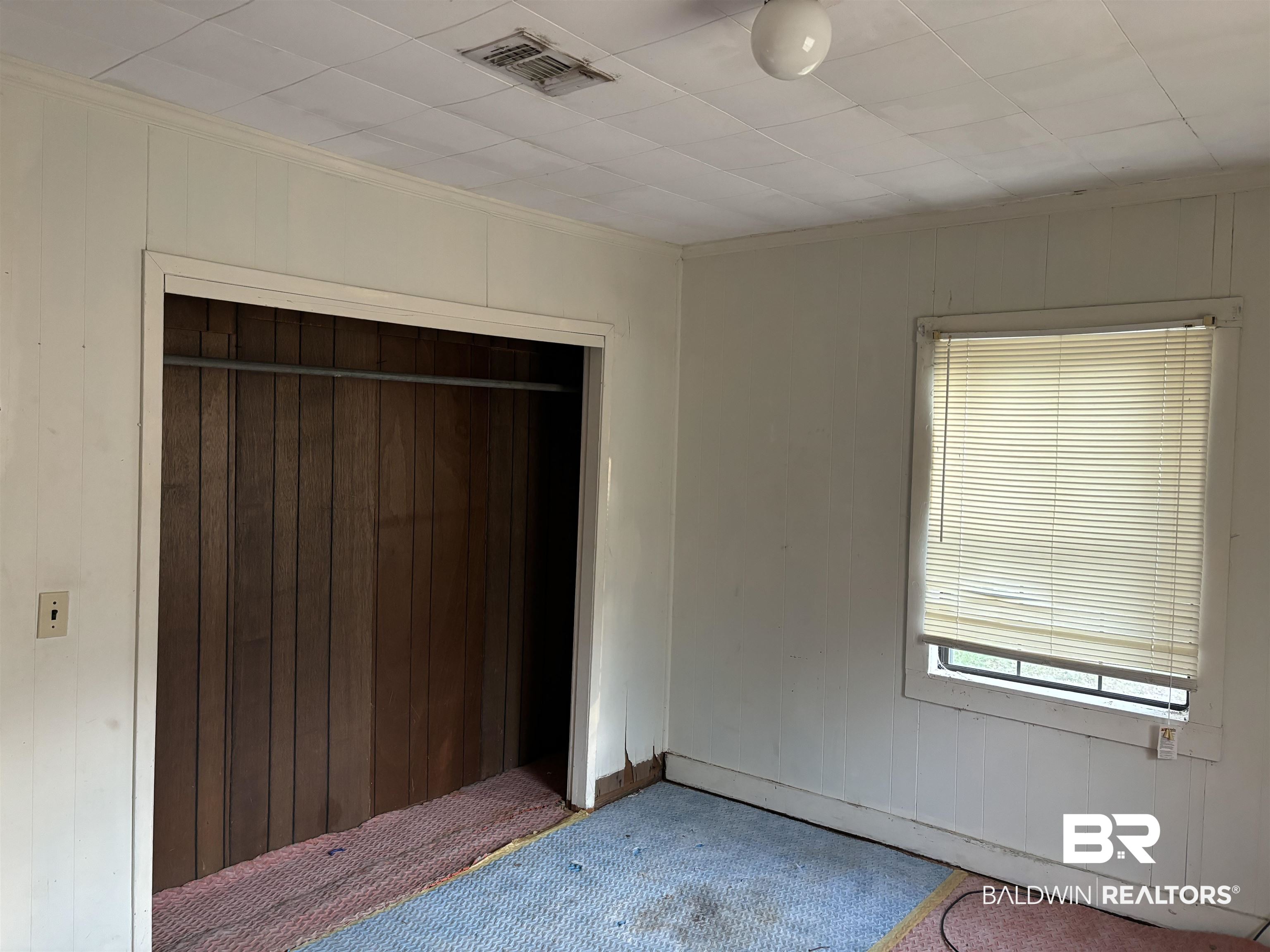 17495 County Road 48 Robertsdale, AL 36567 - Photo 36 of 37 Unfurnished bedroom featuring crown molding, a closet, wood walls, and multiple windows