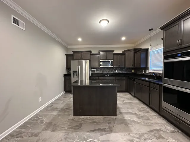 a kitchen with stainless steel appliances granite countertop a refrigerator a sink a stove top oven and granite counter tops